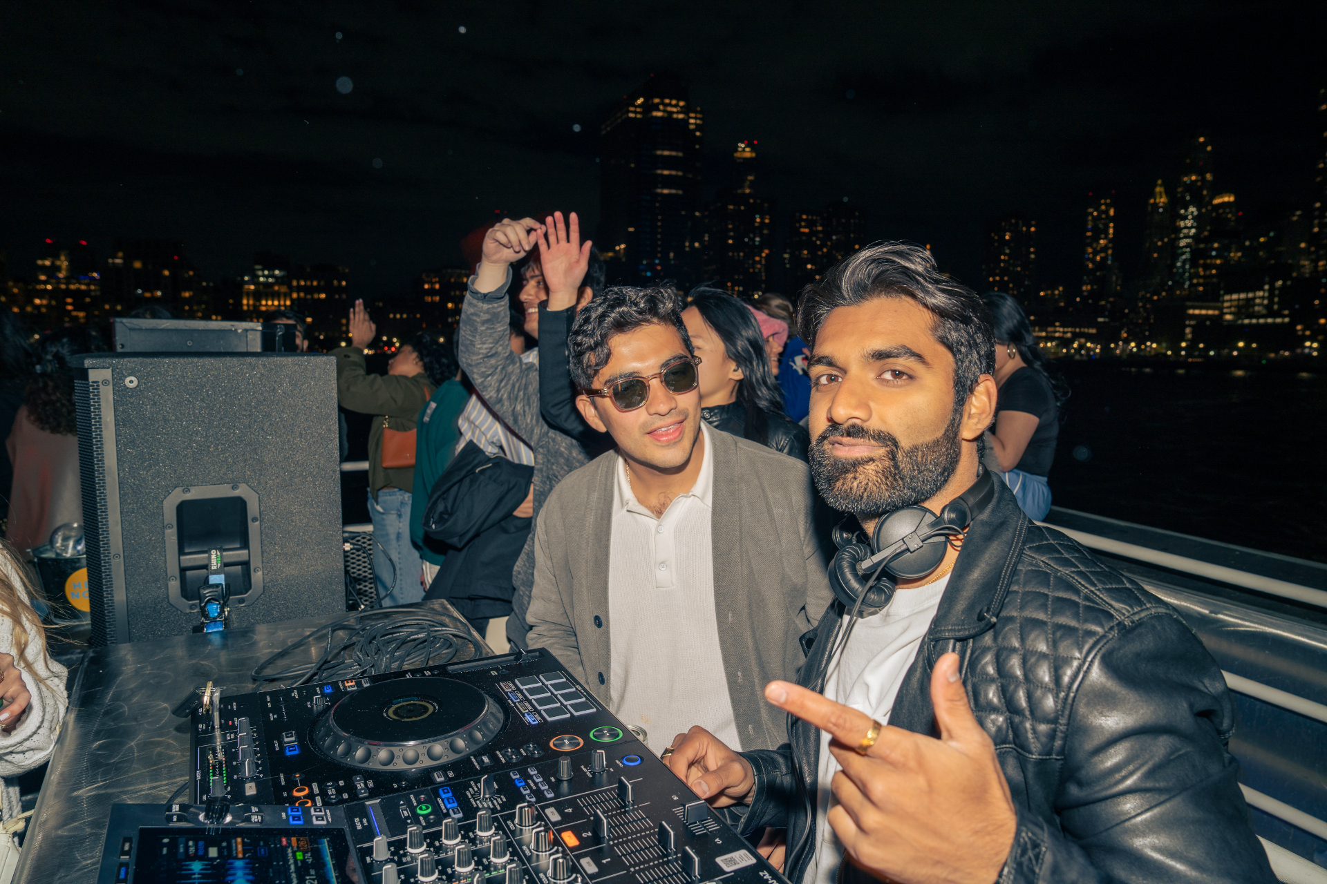 DJ set on a private NYC party boat at night with the Manhattan skyline behind